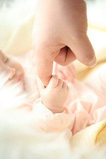 Schlafendes Baby greift Finger eines Erwachsenen